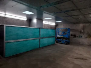 Semi-downdraft spray booth interior at Terex Campsie showing synthetic filter media rear wall and perforated ceiling plenum